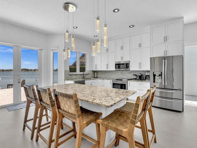 13381 SW 151st Ter, Miami, FL 33186 - kitchen featuring appliances with stainless steel finishes, a sink, decorative backsplash, white cabinetry, and a center island