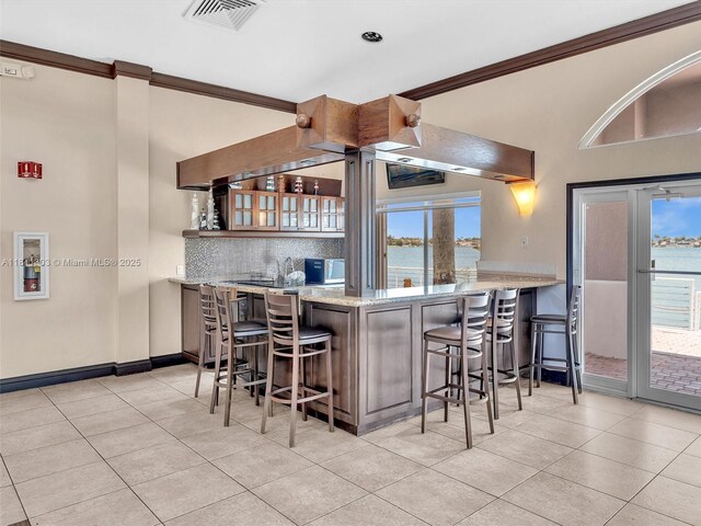 13381 SW 151st Ter, Miami, FL 33186 - kitchen featuring ornamental molding, light tile patterned floors, tasteful backsplash, a kitchen bar, and a water view