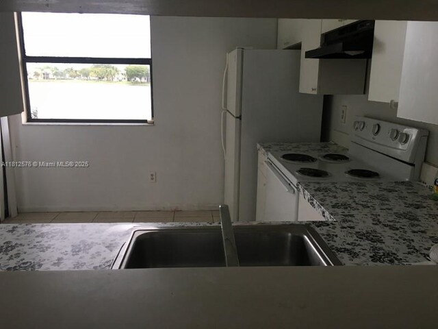 1061 Jefferson Dr Unit 1061B, Homestead, FL 33034 - kitchen with under cabinet range hood, white cabinetry, electric range, tile patterned flooring, and a sink
