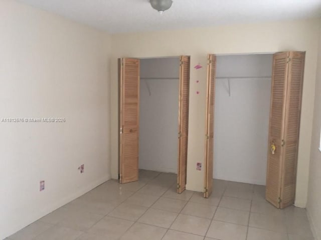 1061 Jefferson Dr Unit 1061B, Homestead, FL 33034 - unfurnished bedroom featuring light tile patterned floors and multiple closets