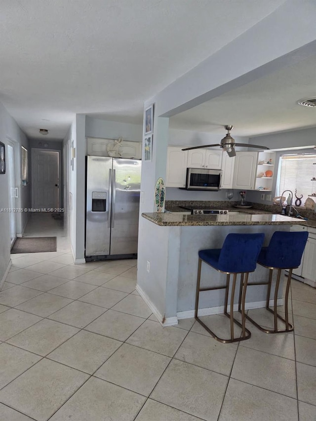 1601 SW 2nd Ave, Pompano Beach, FL 33060 - kitchen with stainless steel appliances, white cabinetry, a breakfast bar, and light tile patterned floors