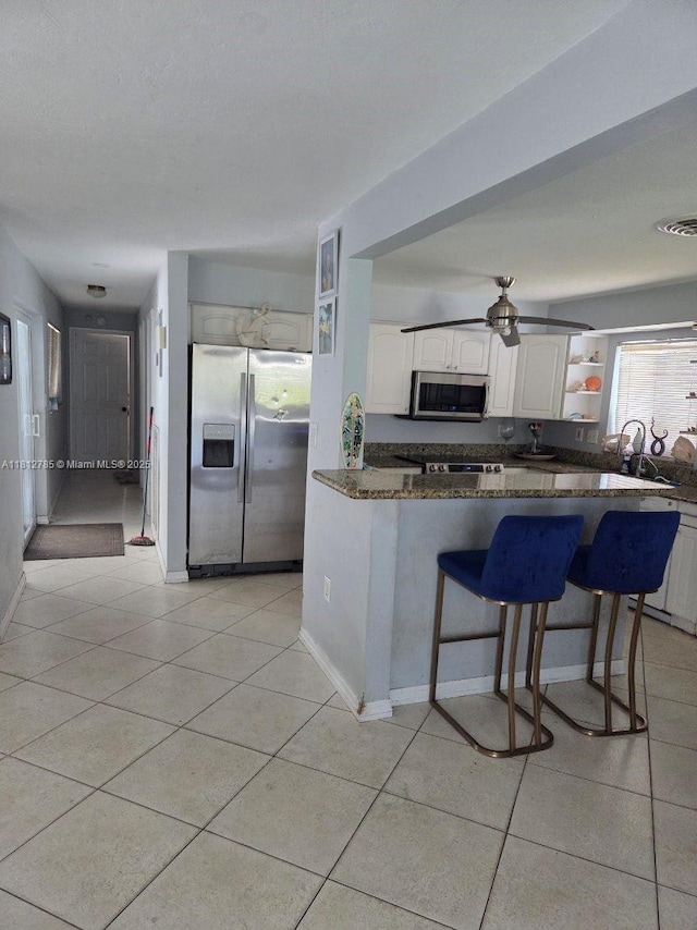 1601 SW 2nd Ave, Pompano Beach, FL 33060 - kitchen featuring appliances with stainless steel finishes, white cabinetry, a kitchen breakfast bar, dark stone counters, and light tile patterned floors