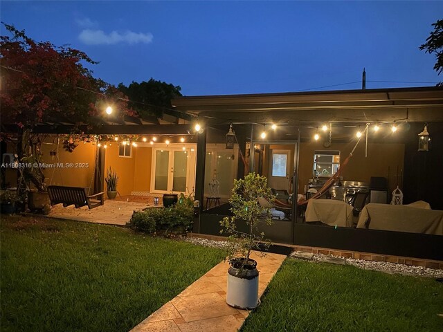 991 Dove Ave, Miami Springs, FL 33166 - back of house at night featuring a yard, french doors, and a patio area
