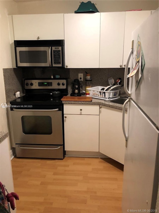 17255 SW 95th Ave Unit D-349, Palmetto Bay, FL 33157 - kitchen with stainless steel appliances, white cabinets, light wood-type flooring, and tasteful backsplash