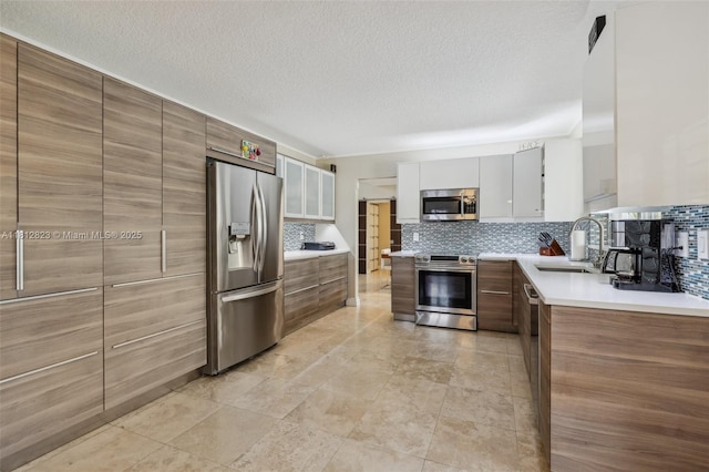 15050 E Falcons Lea Dr, Davie, FL 33331 - kitchen featuring stainless steel appliances, a sink, decorative backsplash, light countertops, and a textured ceiling