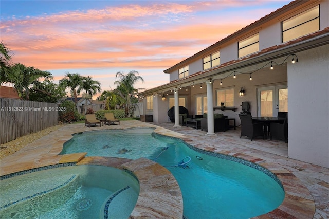 15050 E Falcons Lea Dr, Davie, FL 33331 - pool at dusk with a fenced backyard, outdoor lounge area, a patio area, french doors, and a pool with connected hot tub