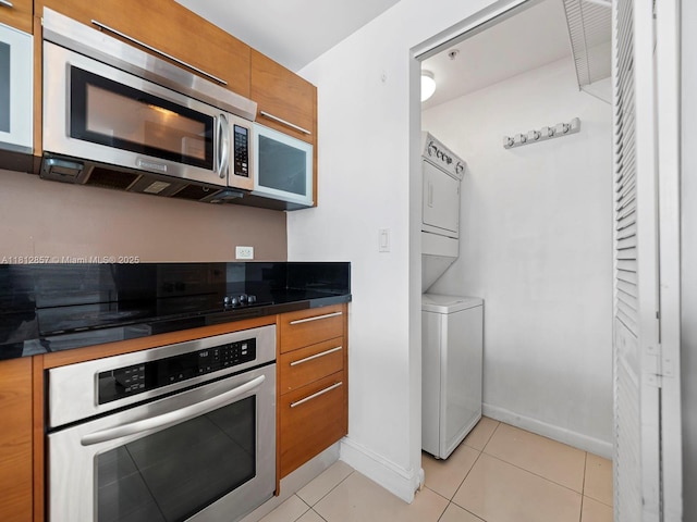 253 NE 2nd St Unit 3108, Miami, FL 33132 - kitchen featuring appliances with stainless steel finishes, stacked washer and clothes dryer, brown cabinets, dark countertops, and baseboards
