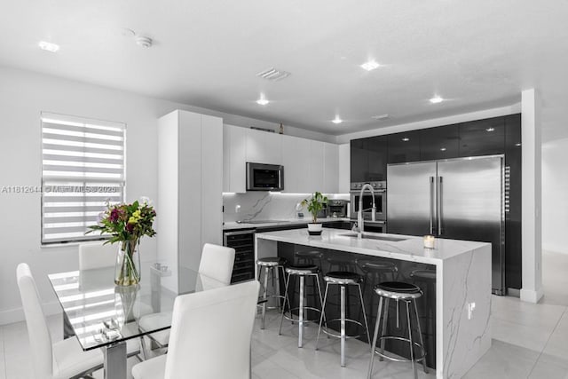 10023 NW 89th Ter, Doral, FL 33178 - kitchen with stainless steel appliances, a sink, modern cabinets, a breakfast bar area, and a kitchen island with sink