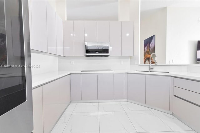 8902 NW 148th St, Miami Lakes, FL 33018 - kitchen featuring modern cabinets, a sink, stainless steel microwave, light countertops, and light marble finish floors