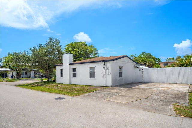 504 SW 5th Ave, Hallandale Beach, FL 33009 - view of side of home featuring a gate, stucco siding, and a chimney