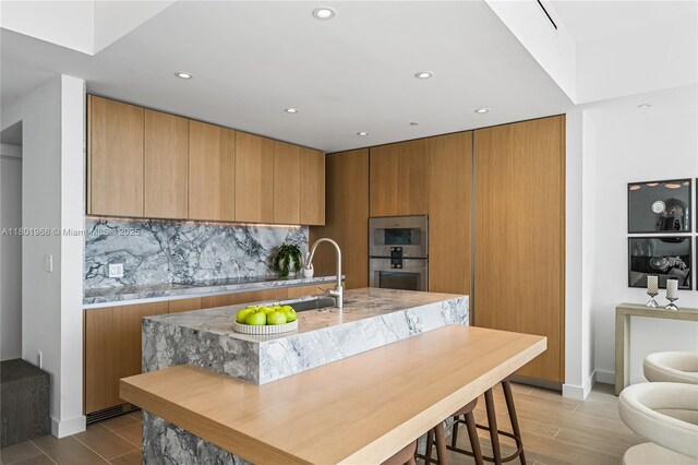 500 Alton Rd Unit 1603, Miami Beach, FL 33139 - kitchen featuring stainless steel double oven, backsplash, a sink, recessed lighting, and brown cabinetry