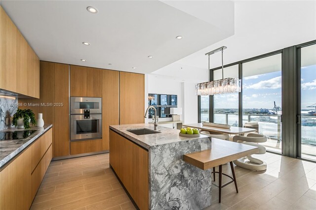 500 Alton Rd Unit 1603, Miami Beach, FL 33139 - kitchen with a sink, modern cabinets, black electric cooktop, light stone countertops, and expansive windows