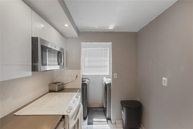 8022 SW 151st Ct Unit 603, Miami, FL 33193 - kitchen with stainless steel microwave, white range with electric stovetop, white cabinets, backsplash, and washing machine and clothes dryer