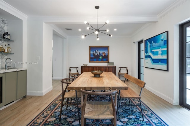 621 NE 55th St, Miami, FL 33137 - dining room featuring light wood-style flooring, ornamental molding, a chandelier, baseboards, and bar area