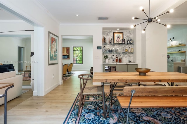 621 NE 55th St, Miami, FL 33137 - dining space with a bar, crown molding, light wood-type flooring, a chandelier, and baseboards