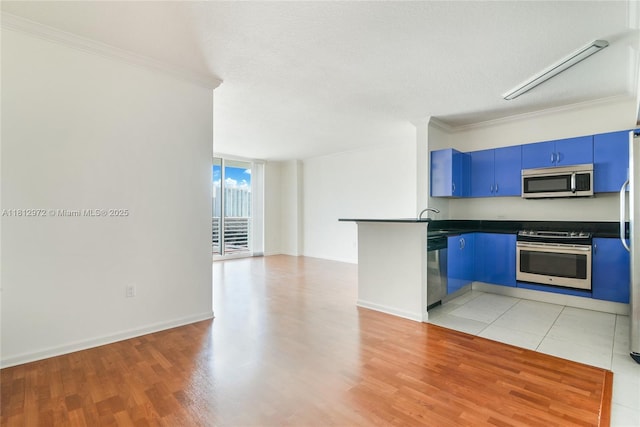18800 NE 29th Ave Unit 1011, Aventura, FL 33180 - kitchen with appliances with stainless steel finishes, blue cabinetry, crown molding, dark countertops, and a peninsula