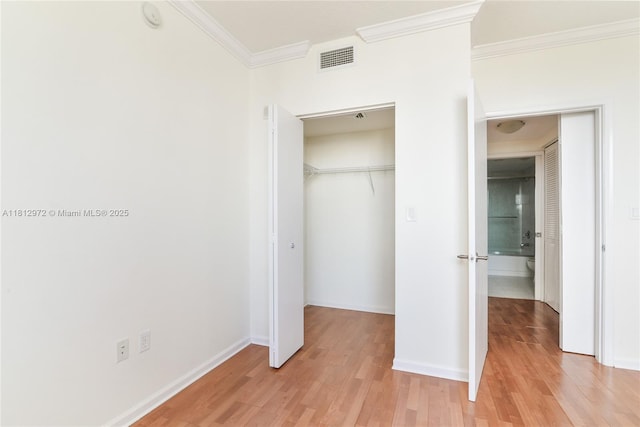 18800 NE 29th Ave Unit 1011, Aventura, FL 33180 - unfurnished bedroom featuring ornamental molding, light wood-type flooring, a closet, baseboards, and a walk in closet