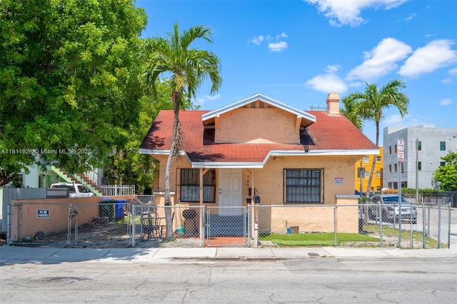 142 NW 10th Ave, Miami, FL 33128 - bungalow-style house with a gate, stucco siding, and a fenced front yard