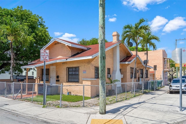 142 NW 10th Ave, Miami, FL 33128 - view of front facade with a chimney, stucco siding, and a fenced front yard