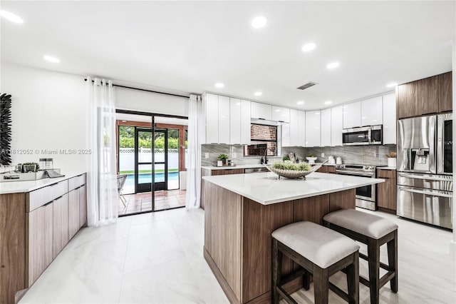 4029 NW 72nd Ave, Coral Springs, FL 33065 - kitchen featuring stainless steel appliances, modern cabinets, a breakfast bar, decorative backsplash, and recessed lighting
