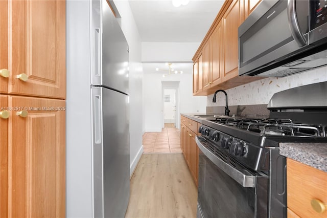 8040 Tatum Waterway Dr Unit 12, Miami Beach, FL 33141 - kitchen with stainless steel appliances, a sink, light wood-type flooring, and baseboards