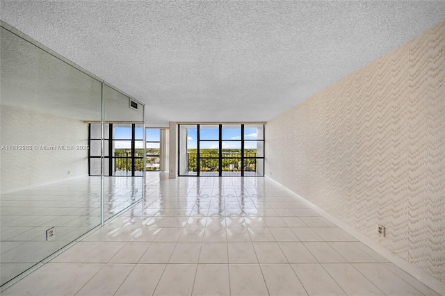 800 Parkview Dr Unit 729, Hallandale Beach, FL 33009 - spare room featuring expansive windows, wallpapered walls, baseboards, a textured ceiling, and light tile patterned flooring