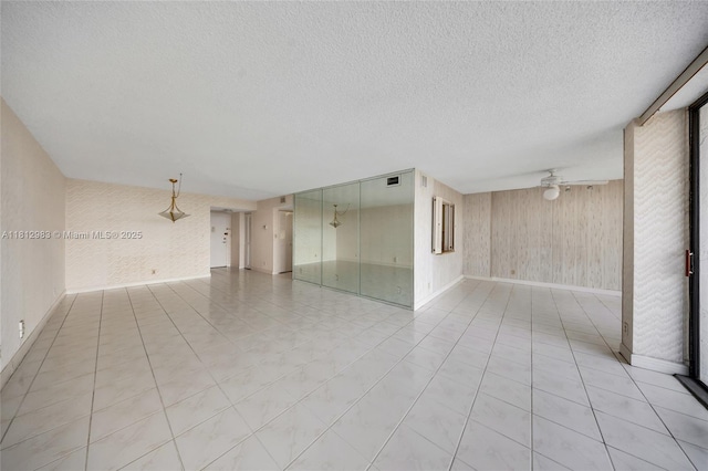 800 Parkview Dr Unit 729, Hallandale Beach, FL 33009 - unfurnished room featuring baseboards, wooden walls, a ceiling fan, and a textured ceiling