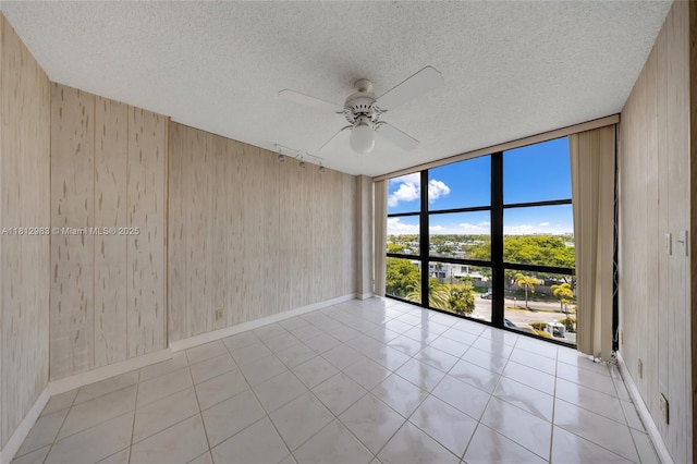 800 Parkview Dr Unit 729, Hallandale Beach, FL 33009 - tiled spare room featuring baseboards, ceiling fan, floor to ceiling windows, wood walls, and a textured ceiling