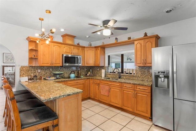 525 NW 32nd Ave, Miami, FL 33125 - kitchen with stainless steel appliances, a peninsula, a ceiling fan, stone counters, and backsplash