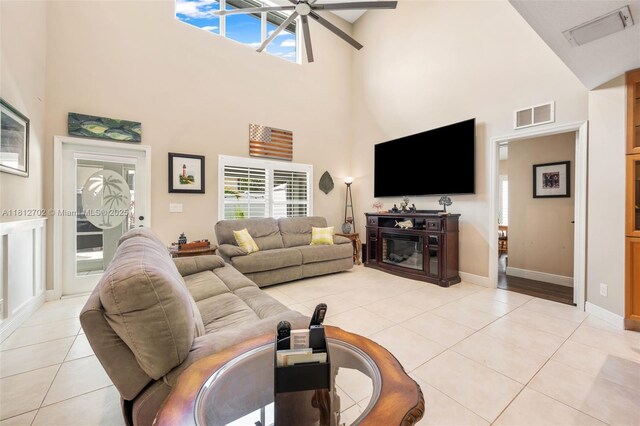 6459 Ungerer St, Jupiter, FL 33458 - living area with high vaulted ceiling, ceiling fan, light tile patterned flooring, a glass covered fireplace, and baseboards