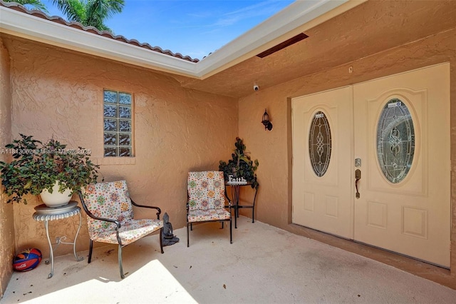 8438 NW 26th Dr, Coral Springs, FL 33065 - doorway to property featuring stucco siding, a patio area, a tile roof, and a surveillance system