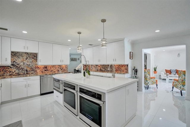 8438 NW 26th Dr, Coral Springs, FL 33065 - kitchen featuring appliances with stainless steel finishes, light tile patterned floors, decorative backsplash, white cabinets, and hanging light fixtures
