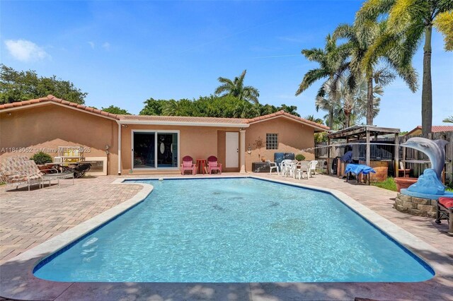 8438 NW 26th Dr, Coral Springs, FL 33065 - rear view of property with a tiled roof, stucco siding, an outdoor pool, and a patio area