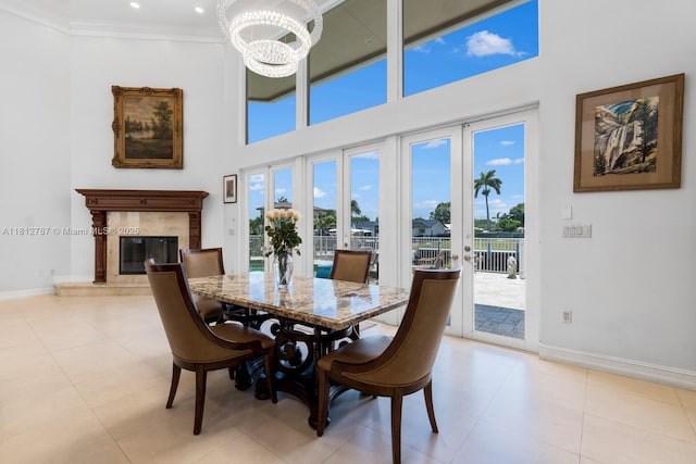 4241 NE 23rd Ter, Lighthouse Point, FL 33064 - dining space featuring a chandelier, a towering ceiling, a high end fireplace, light tile patterned flooring, and french doors