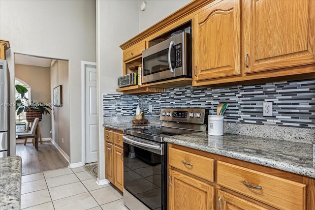 3661 Misty, Woods, FL 32571 - kitchen with stainless steel appliances, light tile patterned flooring, backsplash, and light stone counters