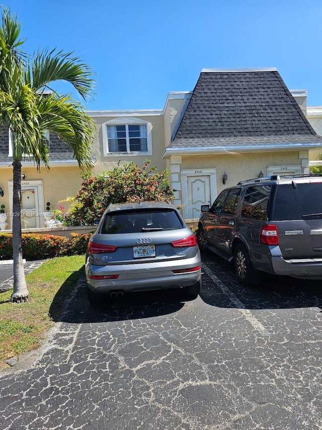 2418 NE 10th St Unit 127, Hallandale Beach, FL 33009 - view of side of home featuring stucco siding, uncovered parking, and a shingled roof