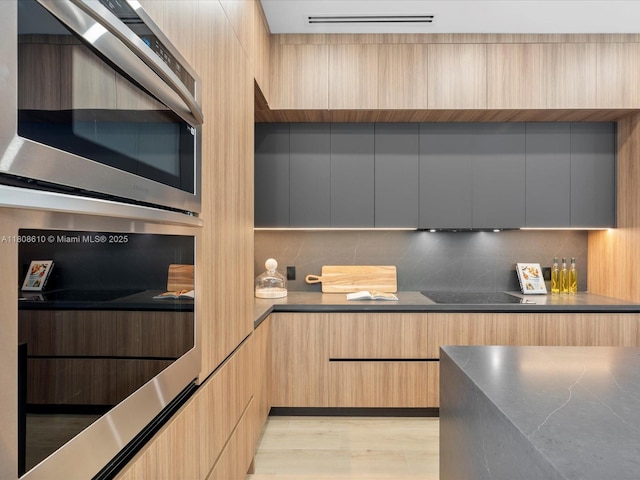 1735 SW 24th Ter, Miami, FL 33145 - kitchen with modern cabinets, double oven, backsplash, black electric stovetop, and light brown cabinetry