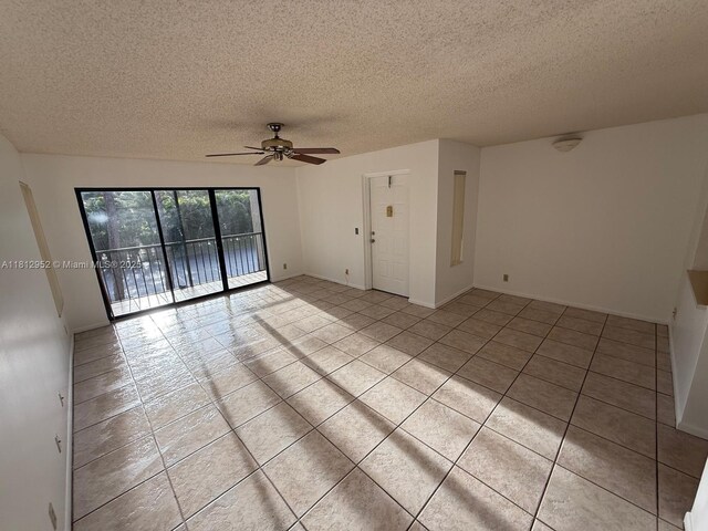721 Sunny Pine Way Unit D2, Green Acres, FL 33415 - empty room with ceiling fan, a textured ceiling, light tile patterned floors, and baseboards