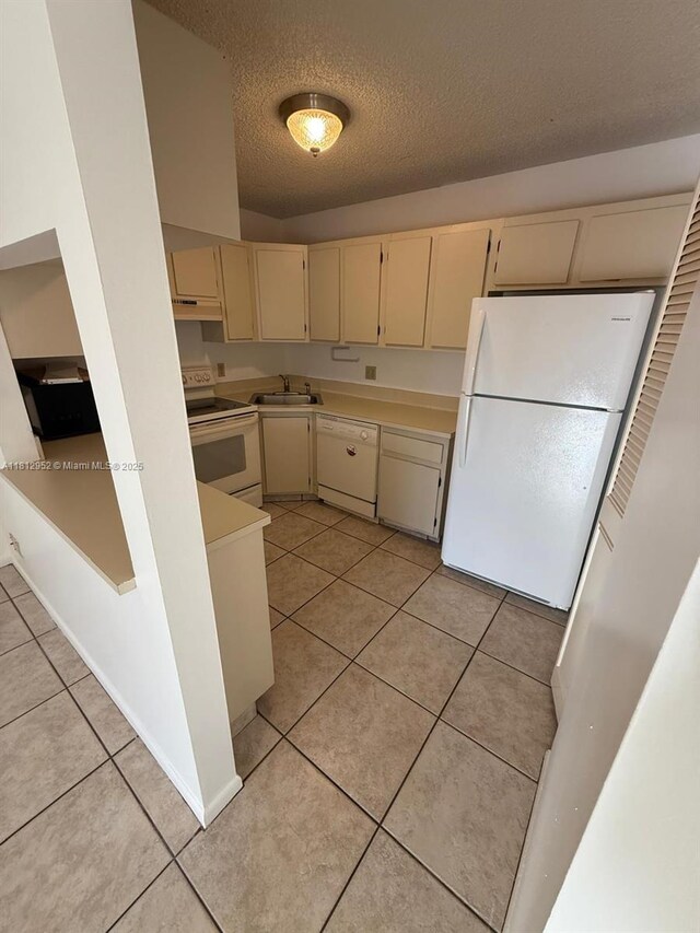 721 Sunny Pine Way Unit D2, Green Acres, FL 33415 - kitchen featuring cream cabinets, white appliances, a sink, light tile patterned flooring, and a textured ceiling