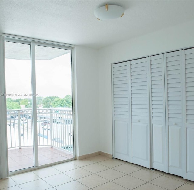 1650 Coral Way Unit 512, Miami, FL 33145 - unfurnished bedroom with expansive windows, access to exterior, light tile patterned floors, a closet, and baseboards
