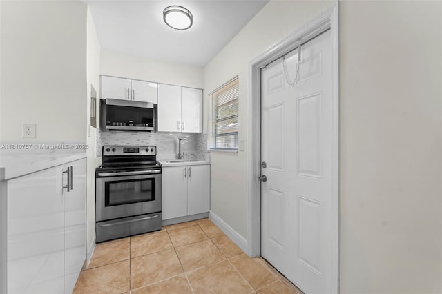 121 SW 5th Ct, Dania Beach, FL 33004 - kitchen featuring stainless steel appliances, a sink, light countertops, white cabinets, and decorative backsplash
