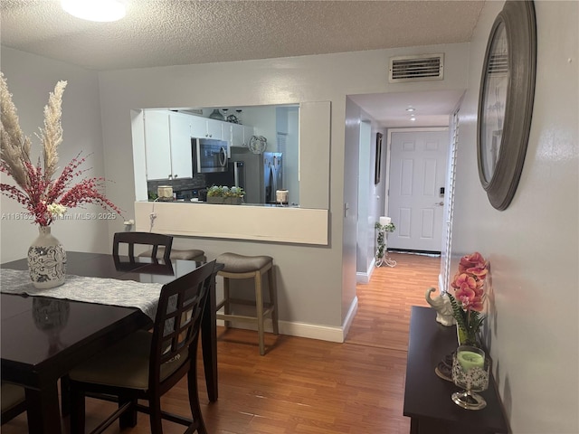 20810 NE 8th Ct Unit 201-18, Miami, FL 33179 - dining space featuring light wood-style floors, baseboards, and a textured ceiling