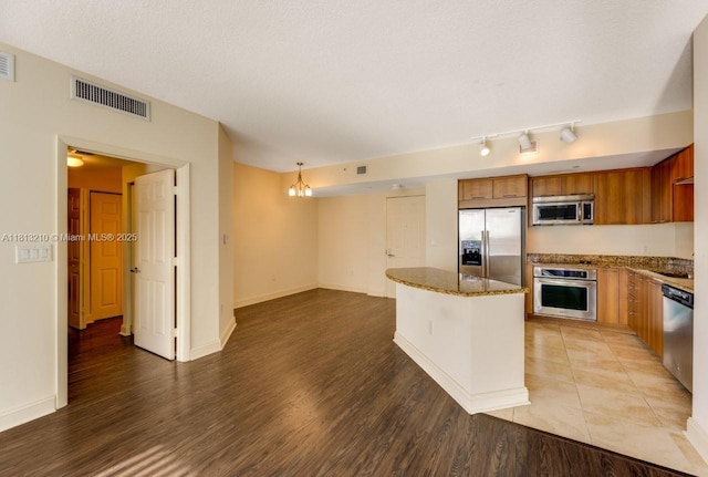 510 NW 84th Ave Unit 541, Plantation, FL 33324 - kitchen with stainless steel appliances, light wood-type flooring, brown cabinetry, and dark stone countertops