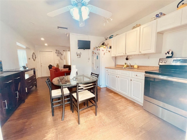 2465 NE 15th Ave, Pompano Beach, FL 33064 - kitchen with electric range, white fridge with ice dispenser, a ceiling fan, white cabinetry, and light wood-style flooring