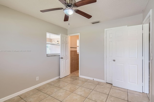 766 NW 35th Ave, Lauderhill, FL 33311 - unfurnished bedroom with light tile patterned floors, baseboards, a textured ceiling, ceiling fan, and tile walls