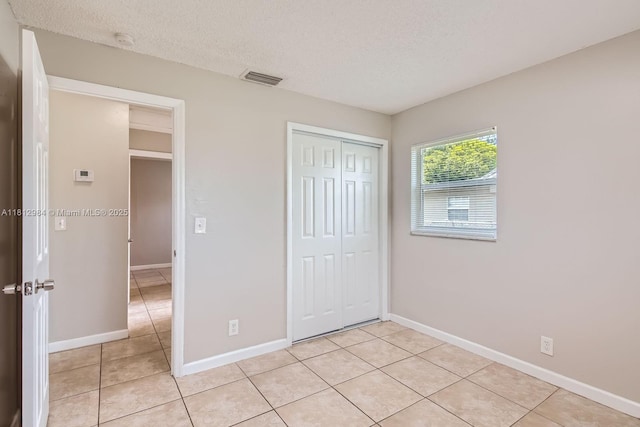 766 NW 35th Ave, Lauderhill, FL 33311 - unfurnished bedroom featuring light tile patterned flooring, baseboards, a textured ceiling, and a closet