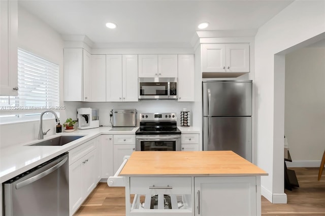 733 NW 30th Ct Unit 2, Wilton Manors, FL 33311 - kitchen with stainless steel appliances, a sink, butcher block countertops, white cabinetry, and light wood-style floors
