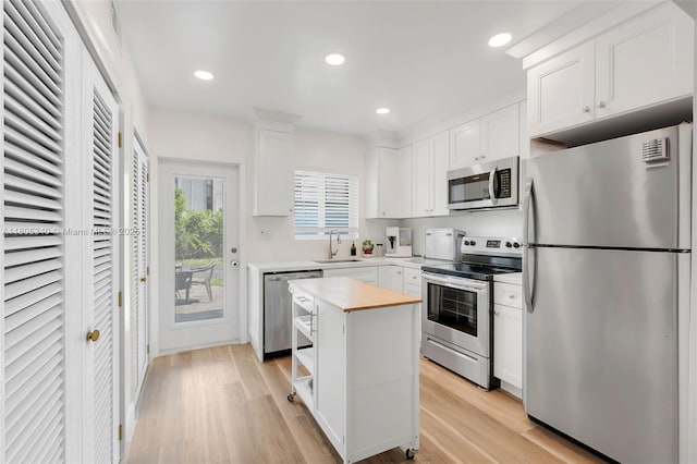 733 NW 30th Ct Unit 2, Wilton Manors, FL 33311 - kitchen with stainless steel appliances, a sink, white cabinets, light wood finished floors, and recessed lighting