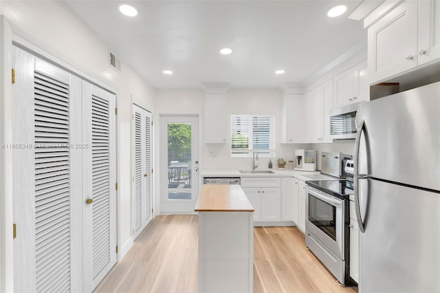 733 NW 30th Ct Unit 2, Wilton Manors, FL 33311 - kitchen featuring stainless steel appliances, white cabinets, a sink, light wood finished floors, and wood counters