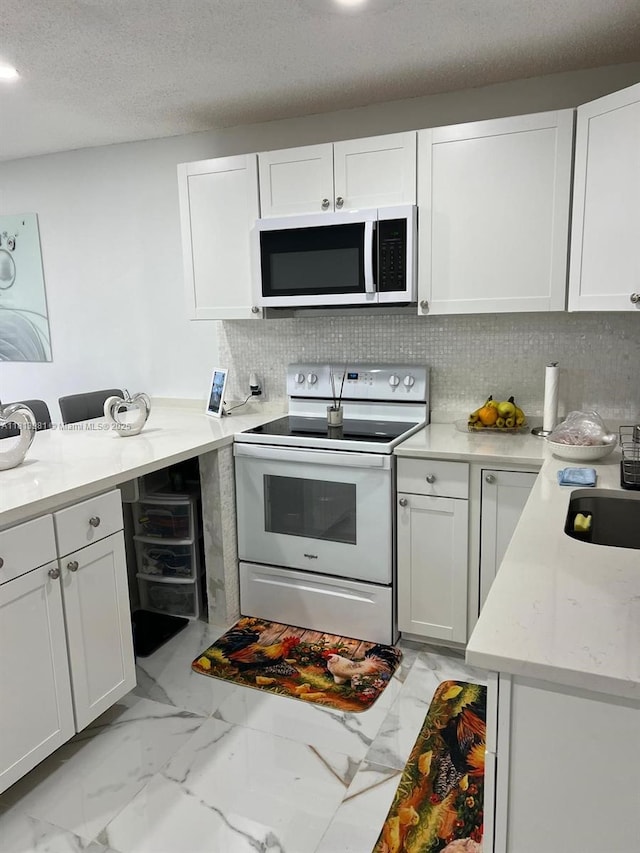 2905 Pierce St Unit 7, Hollywood, FL 33020 - kitchen with stainless steel microwave, white range with electric stovetop, light marble finish flooring, white cabinets, and tasteful backsplash
